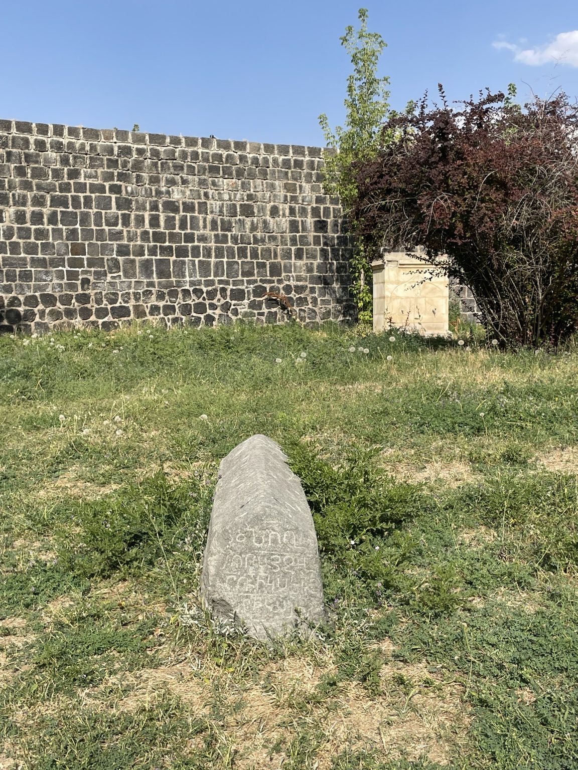 Старое надгробие у базальтовой стены крепости Манцикерт